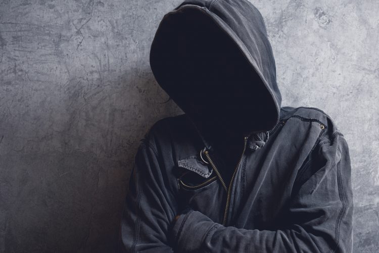 man with face obscured by dark hoodie
